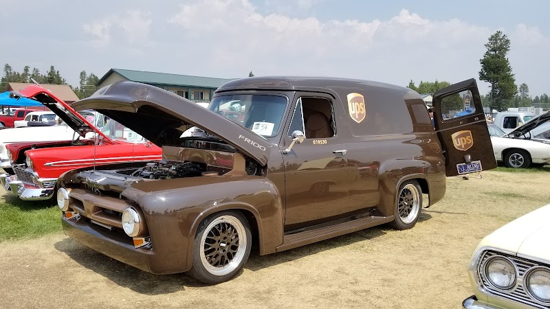 Brown vintage UPS van with hood up and open rear door on a grassy car show at West Yellowstone Heritage Park, Yellowstone National Park.