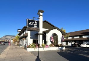 Lodging exterior at Yellowstone National Park showing a white inn building with flower planters and American flags.