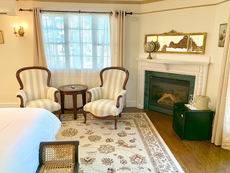 Village Center guest room with two striped upholstered armchairs, small round table, and a fireplace in Acadia National Park.