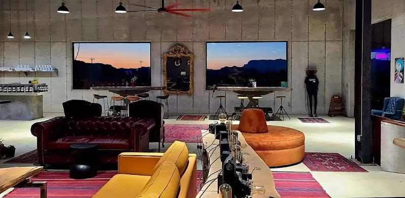 Interior view of a contemporary cafe in Big Bend National Park, with colorful couches, a long service counter, and panoramic sunset windows.