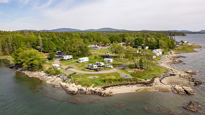 Oceanside KOA Campground at Acadia National Park near Bar Harbor, with RVs parked among green pines along a rocky shoreline.