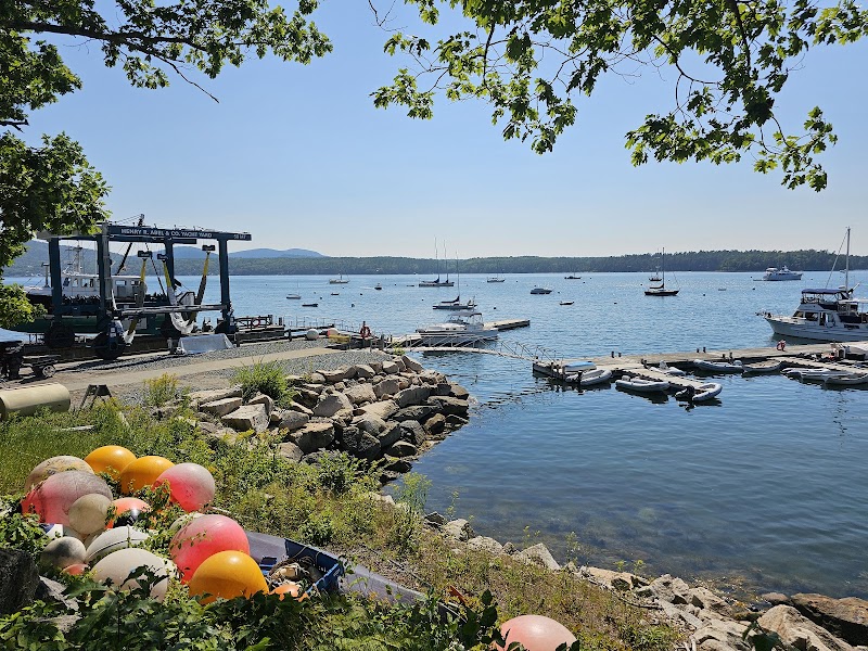 Harbor at Acadia National Park with boats anchored offshore, a rocky shoreline, and colorful lobster buoys in the foreground.