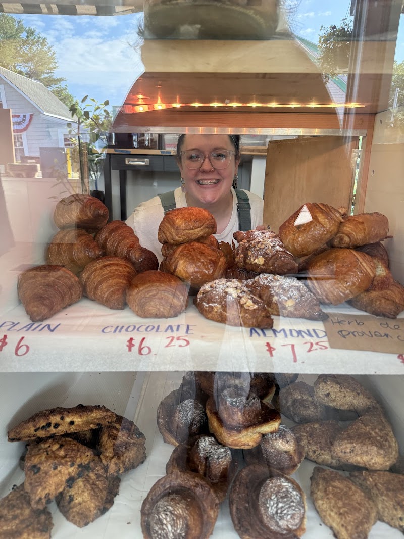 Croissant and pastry display at a cafe inside Acadia National Park, with a smiling staff member behind the counter.