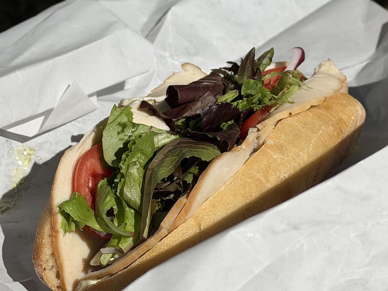 Sub sandwich with turkey, tomato, and mixed greens on a crusty roll, wrapped in white paper at Acadia National Park.