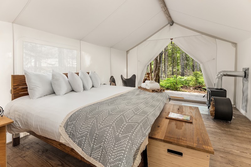 Luxurious glamping tent interior with a large bed, fluffy pillows, and a forest-view opening in Acadia National Park.
