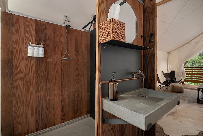 Outdoor wash station with a concrete sink and copper plumbing set against dark wood paneling in Acadia National Park.