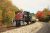 Black striped locomotive leads a green passenger coach along a curved track amid autumn foliage at Acadia National Park.