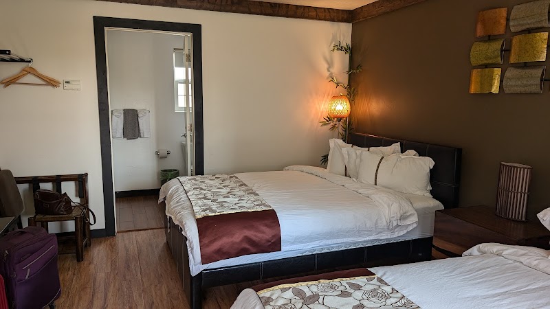 Cozy hotel room with two queen beds, a brown accent wall, wicker lamp, and doorway to an en suite bathroom in Yellowstone National Park.