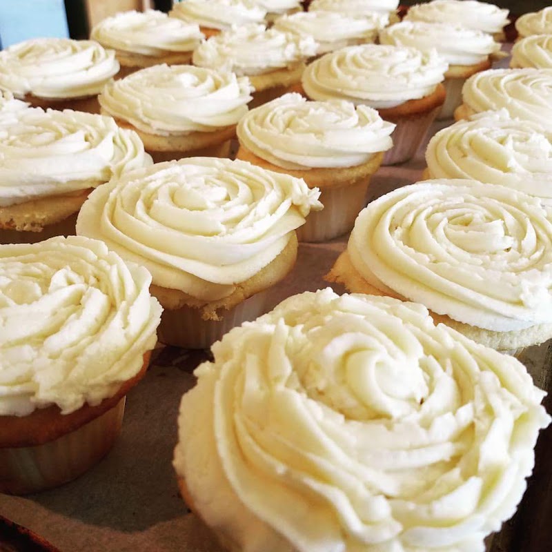 Rows of vanilla cupcakes with piped white frosting on a tray in a bakery kitchen at Yellowstone National Park.