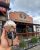 Hand holds chocolate milkshake with drizzle and straw in front of a rustic wooden cafe in Yellowstone National Park.