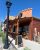Exterior view of a rustic wooden cafe along a sidewalk in Yellowstone National Park, with hanging flower baskets and a vintage lamp.