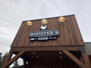 Wooden storefront with a rooster sign advertising a cafe in Yellowstone National Park.