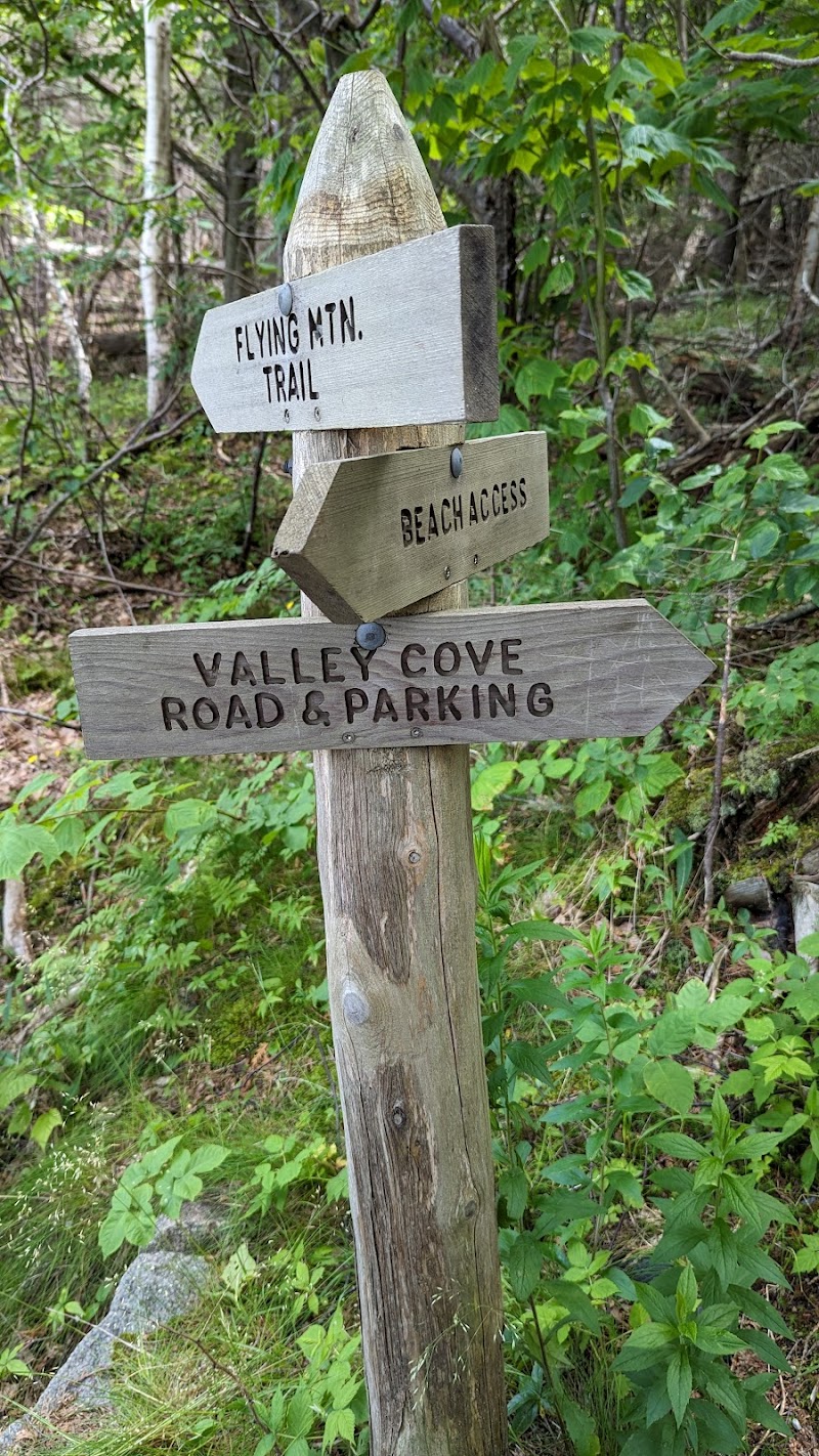 Weathered wooden signpost at Flying Mountain Trailhead in Acadia National Park, pointing to Beach Access and Valley Cove Road and Parking.
