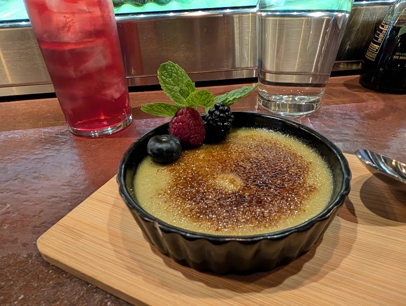 Crème brûlée with a caramelized top, berries and mint garnish, served on a wooden board at Arches National Park cafe.
