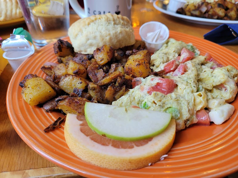Colorful plate in Acadia National Park shows roasted potatoes, vegetable scramble with tomatoes, lime-garnished grapefruit slice, and biscuit.