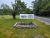 Granite industry sign along a roadside in Acadia National Park, framed by trees and a flower bed.
