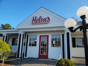 Front view of a white restaurant building with a red door in Ellsworth, Acadia National Park, with blue sky above.