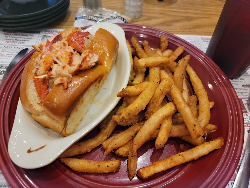 Lobster roll with seasoned fries on a plate in a casual dining setting near Acadia National Park.