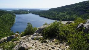Jordan Pond Path Trailhead with rugged granite steps, green shrubs, and a sweeping view of Jordan Pond in Acadia National Park.