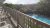 Balcony with a wooden railing and white plastic chairs overlooks a blue pool amid green trees in Acadia National Park.