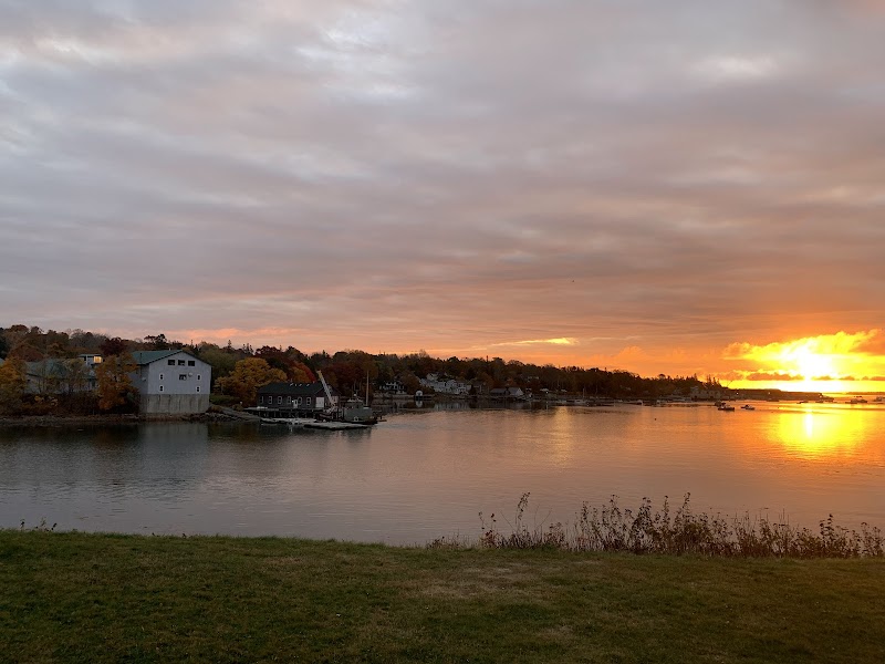 Sunset over a calm harbor with boats docked along a shoreline, pastel sky over Acadia National Park.