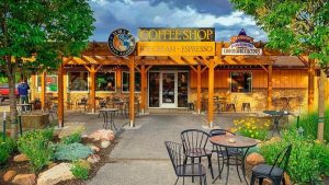Wooden storefront with outdoor seating under a pergola, warm tones, greenery, and stone accents at Arches National Park.