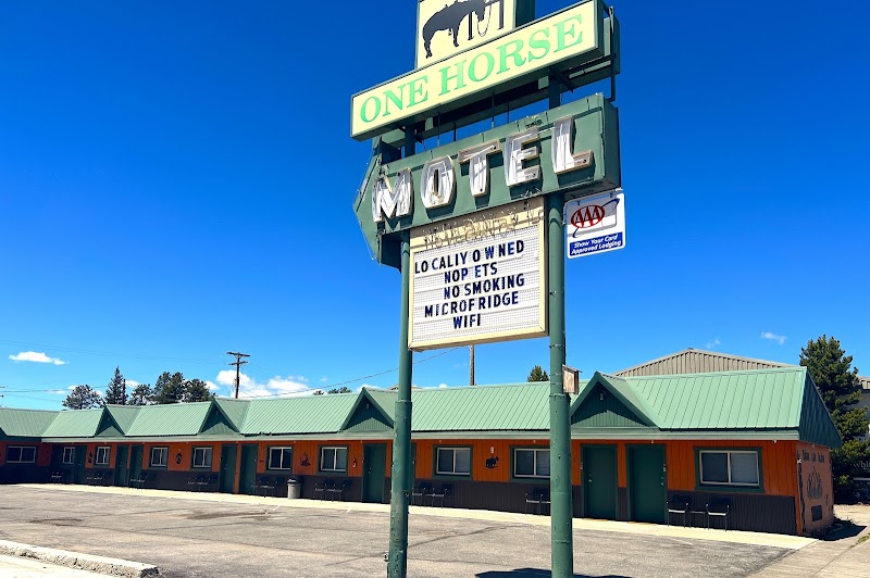 Yellowstone National Park scene with a vintage roadside motel, green roof, orange facade, and a tall sign.