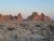Sunlit orange-red badlands spires rise over rocky terraces along a wooden trail in Badlands National Park at dusk.
