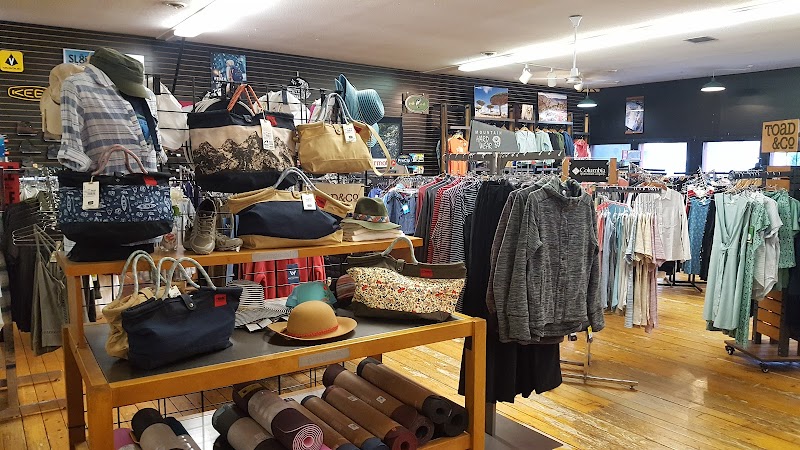 Gift shop interior in Acadia National Park displaying bags, hats, and clothing on shelves and racks.