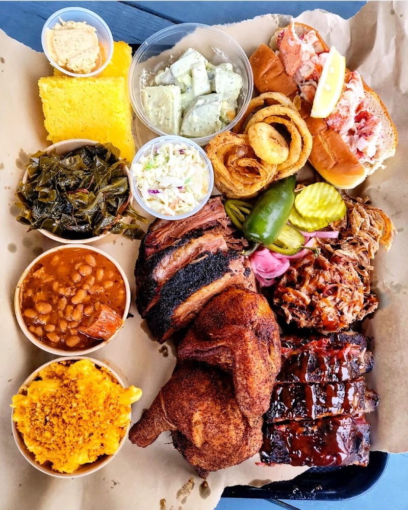 Heaping BBQ platter with ribs, smoked chicken, lobster items, corn bread, greens, beans, pickle, slaw at Acadia National Park.