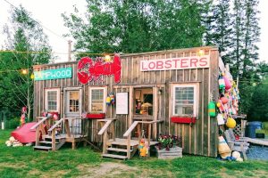 Lobster shack storefront along a rustic wooden building at Acadia National Park near Bar Harbor, with lobster buoys and signs on the exterior.