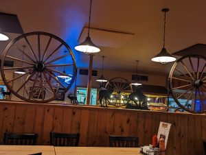 Interior at a Yellowstone National Park restaurant with wooden walls, wagon wheels, and moose silhouettes along a railing.
