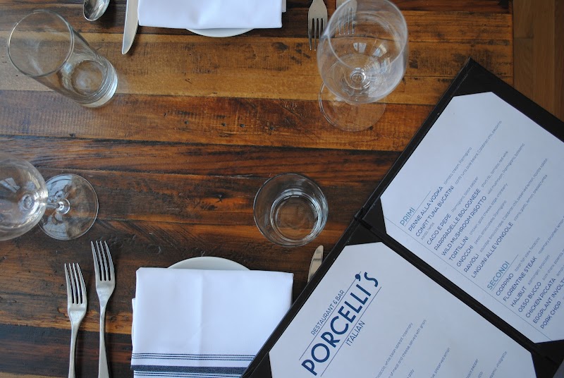 Wooden dining table with napkins, forks, and several wine glasses, plus an open menu in Acadia National Park.