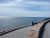 Cyclist rides along a paved coastal road beside a stone seawall in Acadia National Park, ocean and sky ahead.