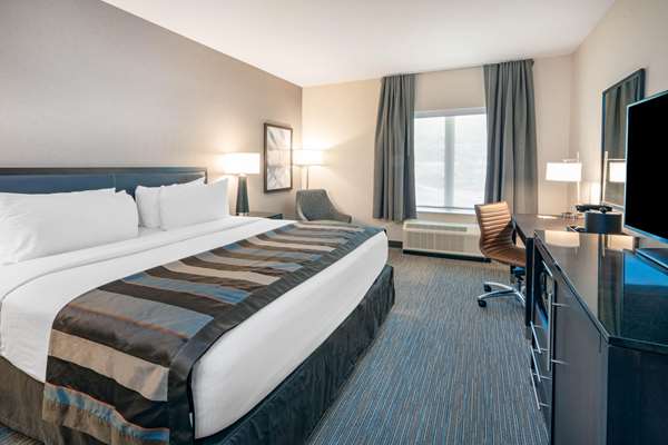 Spacious hotel room with a king bed, striped runner, two lamps, window with blue curtains, desk and chair, Arches National Park.