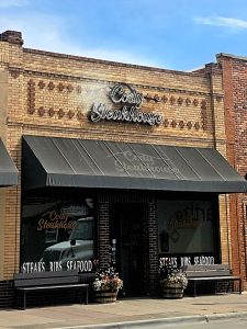 Steakhouse storefront in Yellowstone National Park, brick building with a black awning and planters outside.
