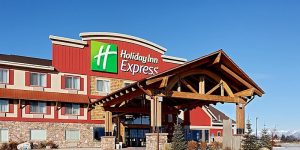 Modern hotel exterior in Kalispell near Glacier National Park, with red siding and a wooden entry canopy.
