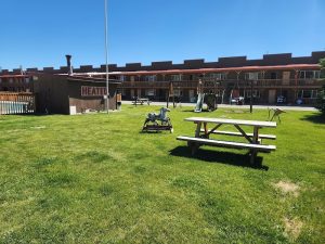 Yellowstone National Park motel courtyard with a picnic table, playground, and small heat shed in the well-kept grassy area.