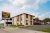 Exterior view of a motel-style lodging near Badlands National Park, with a two-story brick facade and a sunny sky.
