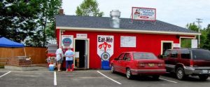 Bright red lobster restaurant building with cars parked in front along a park road in Acadia National Park, a coastal diner scene.