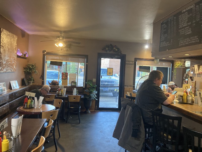 Cozy cafe in Yellowstone National Park with a bar counter, windows, a door outside, patrons eating, and condiment bottles on tabletops.