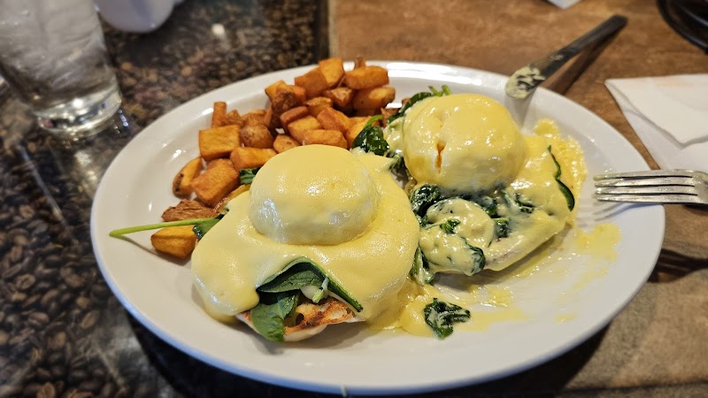 Eggs Benedict with spinach and rich hollandaise on toasted muffins, with roasted potatoes beside, in Yellowstone National Park.
