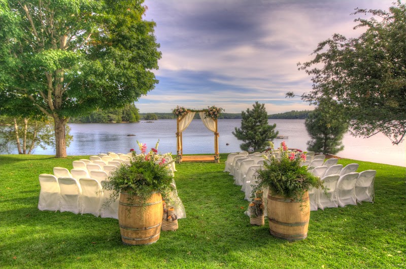 Lakeside wedding ceremony site at Acadia National Park with a wooden arch overlooking the calm water and green lawn.