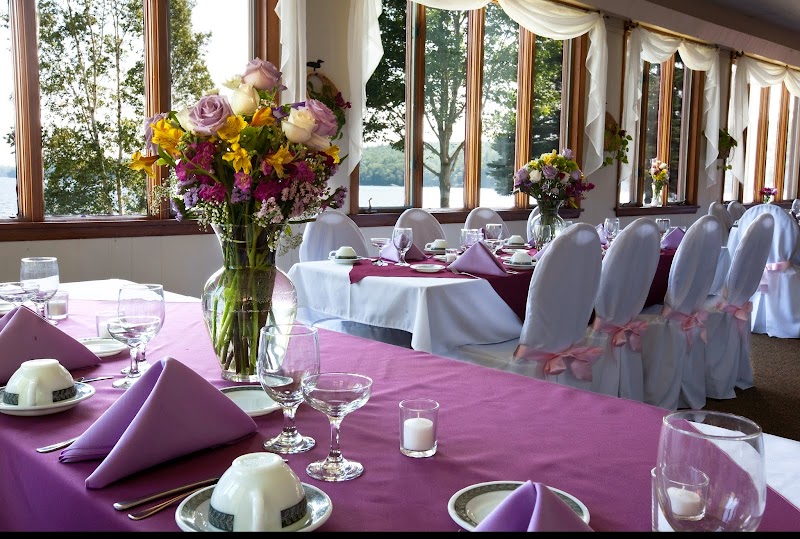 Lakeside banquet hall at Acadia National Park with purple table linens, floral centerpieces and large windows overlooking the lake.