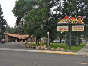 Visitor Center at Yellowstone National Park, with a sign, small building, trees, and manicured lawn.