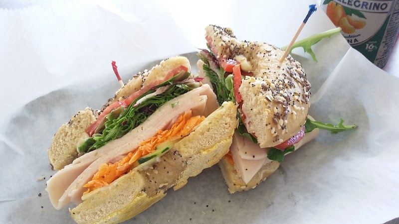 Two sesame bagel sandwiches filled with turkey, lettuce, sprouts and carrots on parchment, Arches National Park.