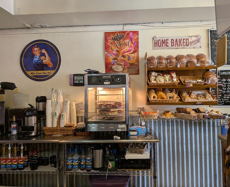 Arches National Park cafe counter with a pastry oven, shelves of bagels and breads, cups, and a 'HOME BAKED' sign.