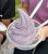 Lavender soft-serve ice cream swirled in a clear cup with two plastic spoons, held outdoors in Acadia National Park.
