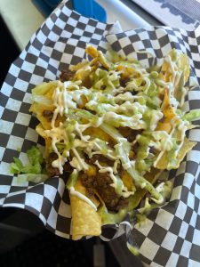 Loaded crunchy tacos with seasoned beef, lettuce, cheese, and ranch-style sauce in a checkered basket at Badlands National Park.