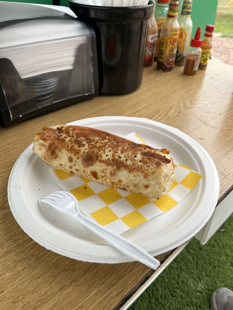 Grilled burrito on a white plate with yellow checkered parchment and a plastic fork at Badlands National Park.